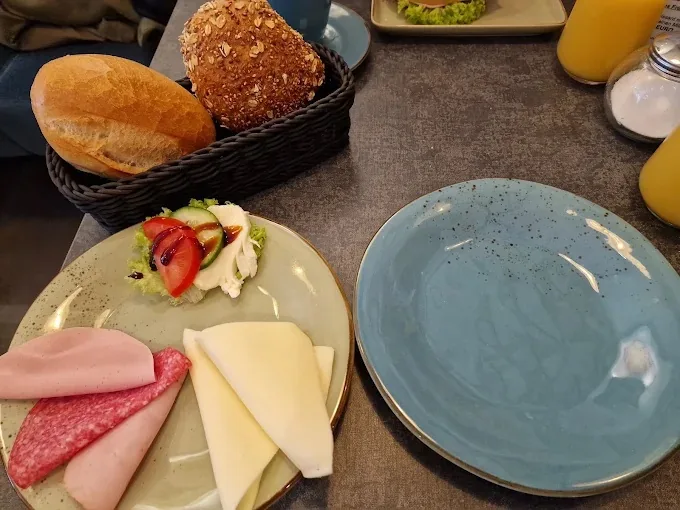 Frühstück im Café: Brötchenkorb, Aufschnitt, Käse und Orangensaft